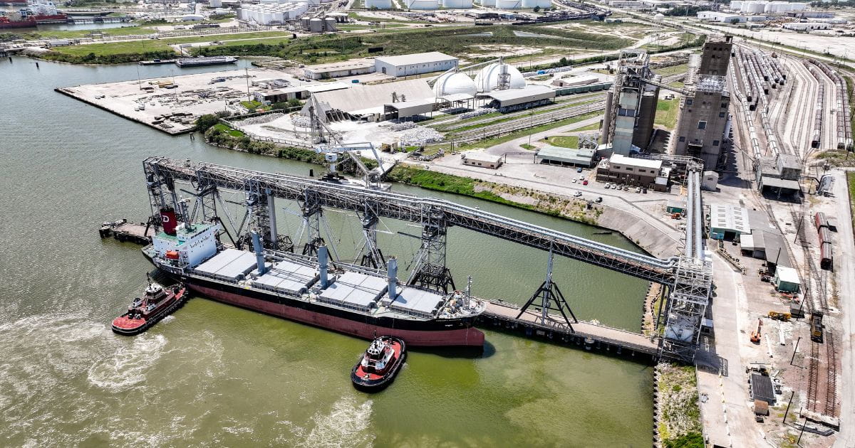 A ship being pushed to a dock by tugboats.  