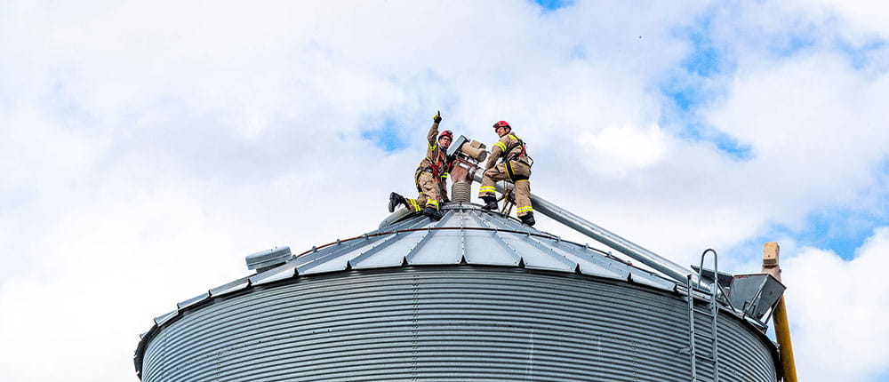 Two firefighters on top of a grain bin