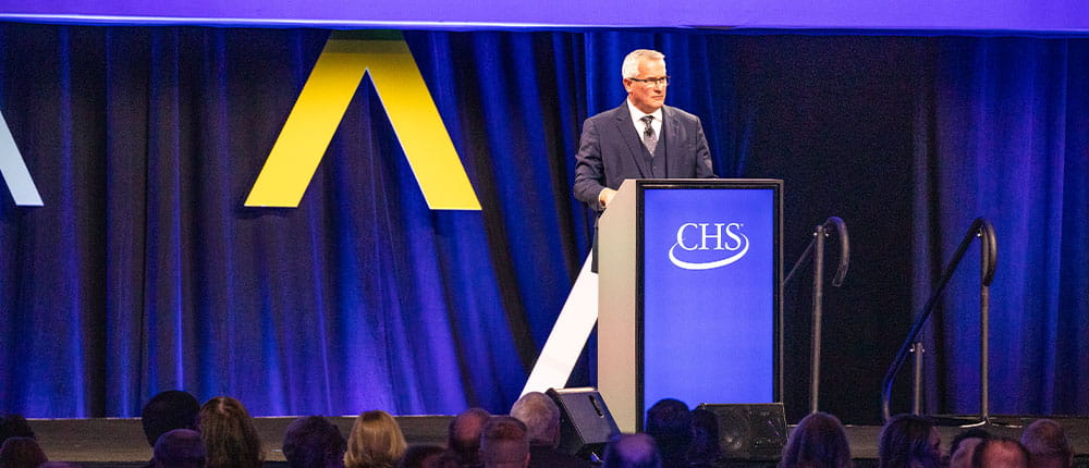 CHS Board of Director chair Dan Schurr standing at a podium at 2023 Annual Meeting